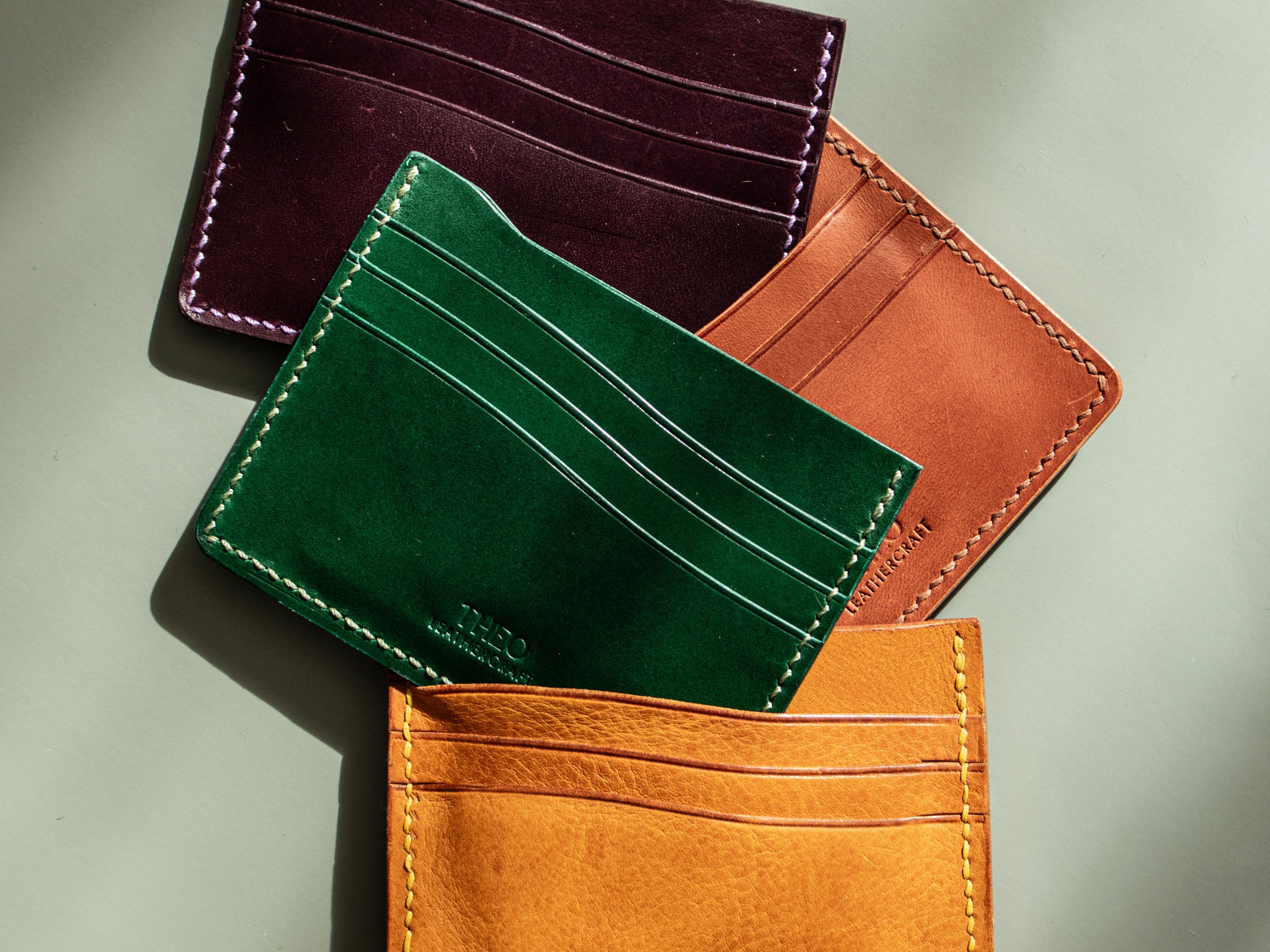 Four leather card holders in different colours on a neutral background