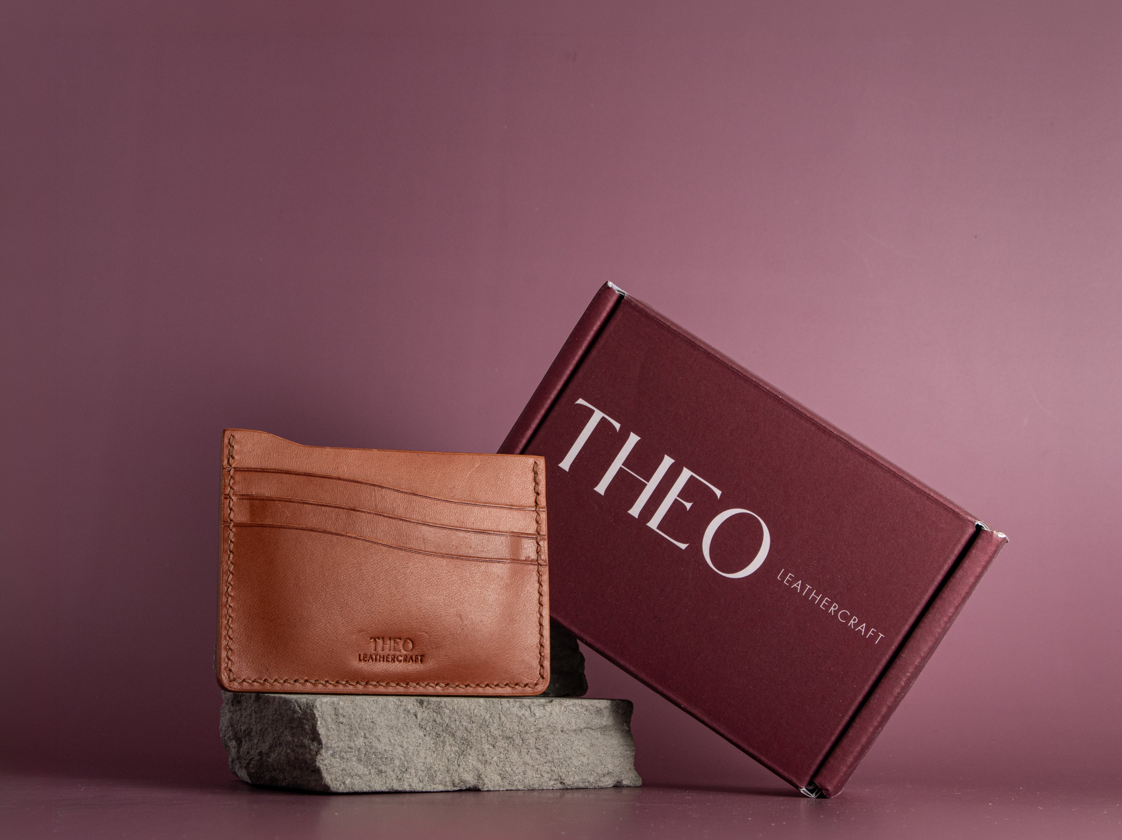 Brown leather cardholder and packaging  with 'THEO Leathercraft' branding on a purple background