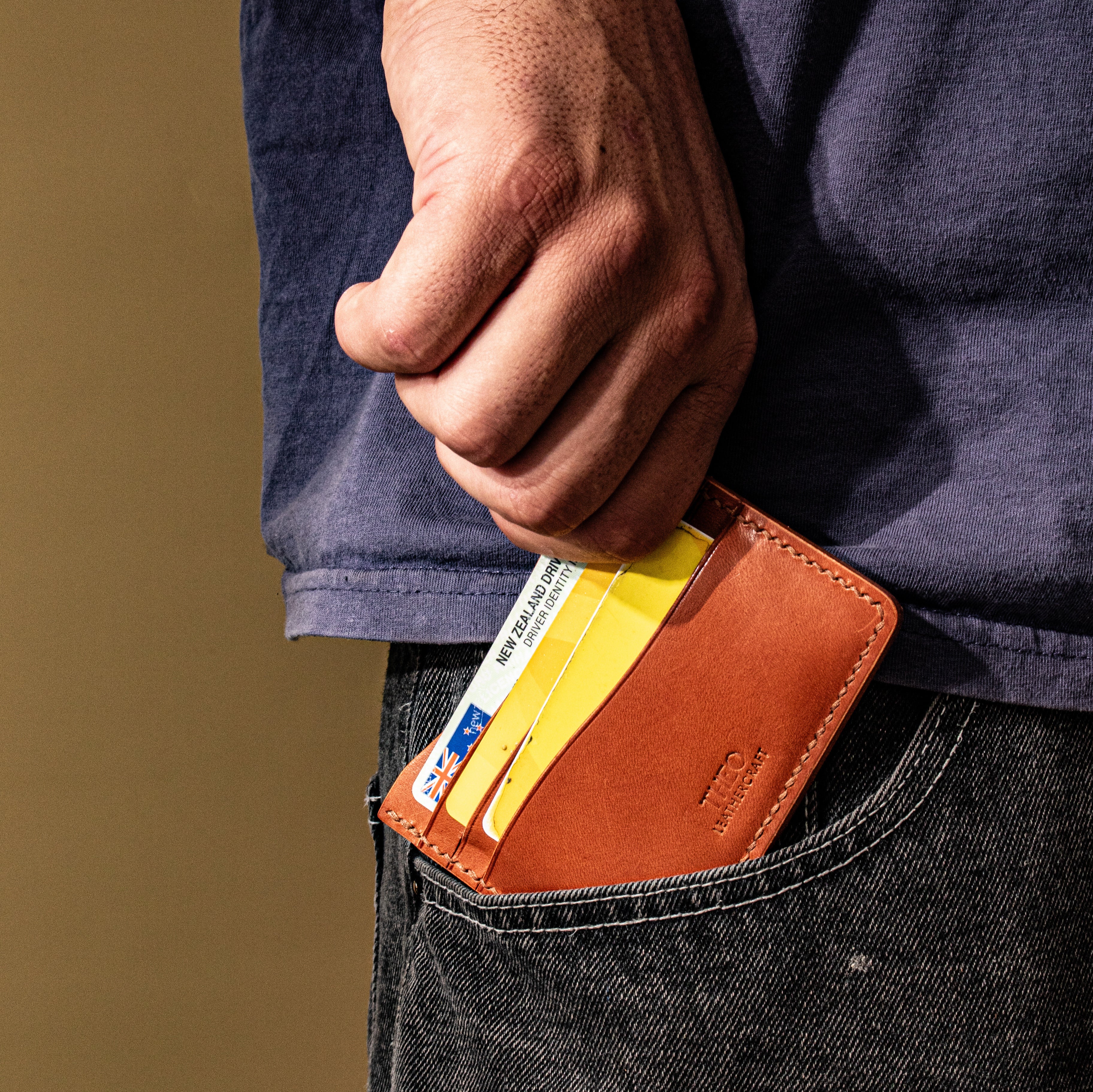 Person inserting a brown leather wallet with cards into their pocket