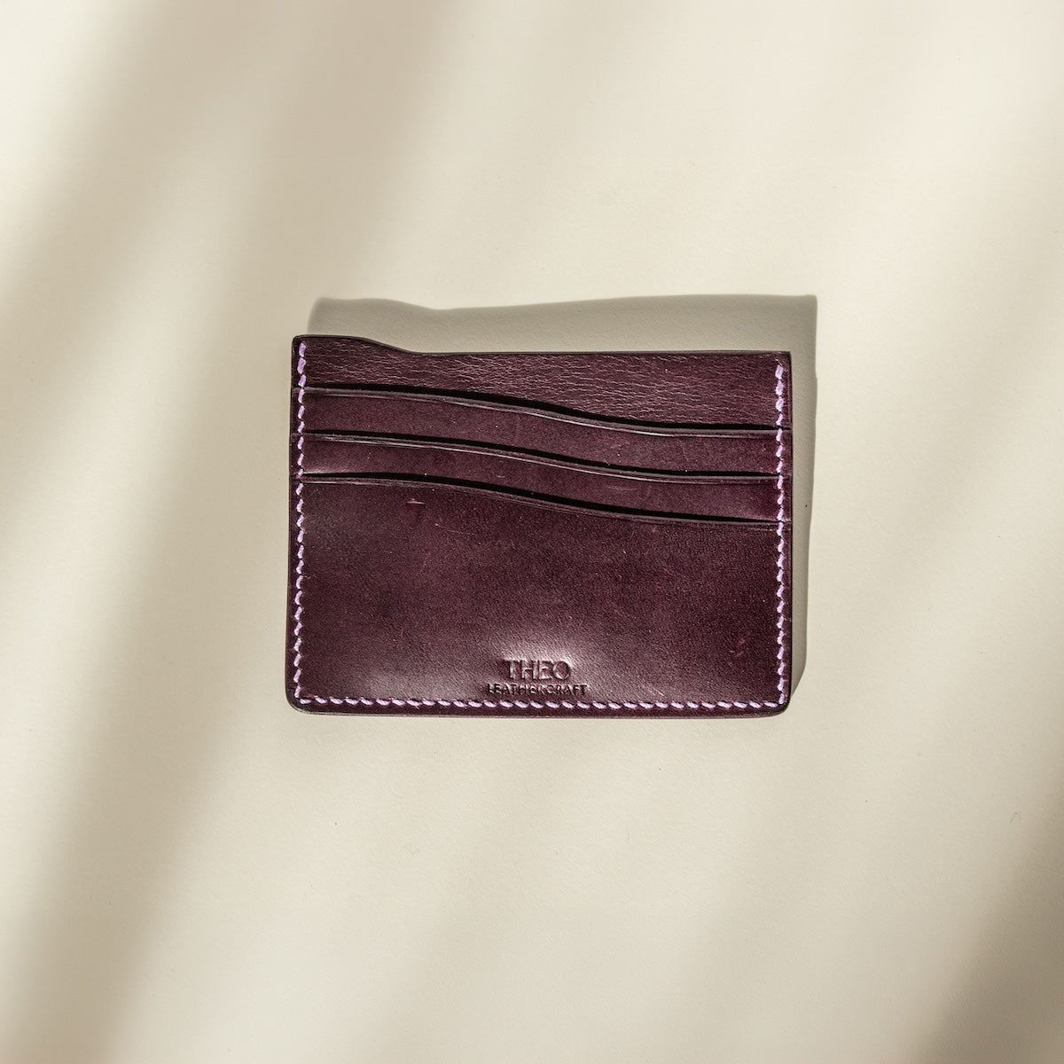 Purpler buttero leather cardholder with visible brand name on a beige background